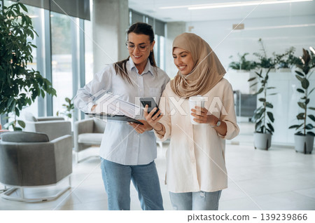 Muslim clothing. Two women are indoors in the modern hall of building at daytime Muslim clothing. Two women are indoors in the modern hall of building at daytime 139239866