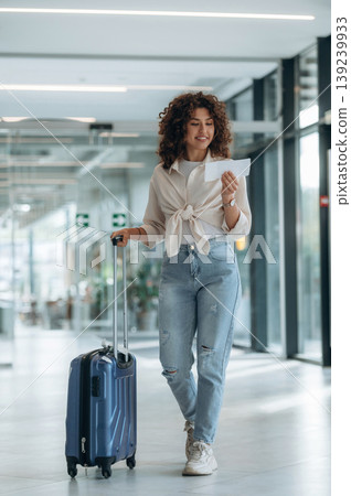 Tourist is with document. Beautiful woman is in airport hall with suitcase Tourist is with document. Beautiful woman is in airport hall with suitcase 139239933