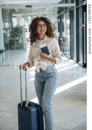 Holding the ticket. Beautiful woman is in airport hall with suitcase Holding the ticket. Beautiful woman is in airport hall with suitcase 139240058