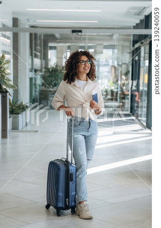 Holding the ticket. Beautiful woman is in airport hall with suitcase Holding the ticket. Beautiful woman is in airport hall with suitcase 139240059