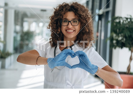 Heart, love gesture by hands. Woman doctor is standing indoors in the clinic Heart, love gesture by hands. Woman doctor is standing indoors in the clinic 139240089