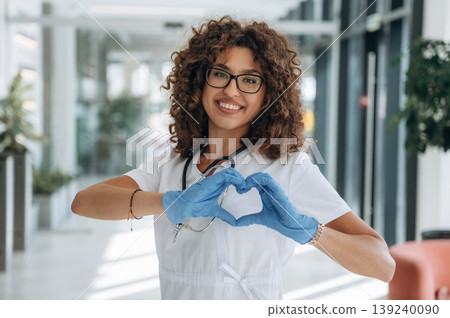 Heart, love gesture by hands. Woman doctor is standing indoors in the clinic Heart, love gesture by hands. Woman doctor is standing indoors in the clinic 139240090