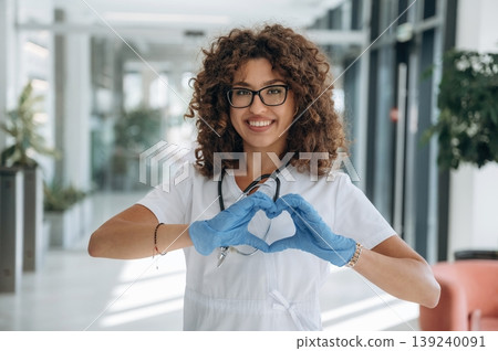 Heart, love gesture by hands. Woman doctor is standing indoors in the clinic Heart, love gesture by hands. Woman doctor is standing indoors in the clinic 139240091