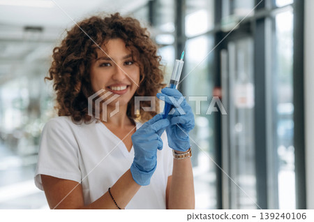 Big syringe in hands. Woman doctor is standing indoors in the clinic 139240106