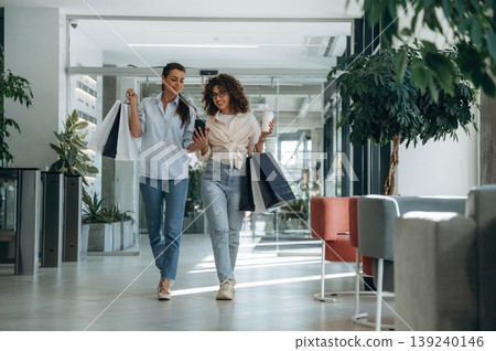 Front view, walking. Two female friends are in the supermarket with shopping bags 139240146