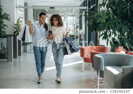 Front view, walking. Two female friends are in the supermarket with shopping bags 139240147