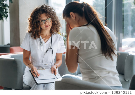 Consultation with doctor. Two women are indoors in the modern hall of building at daytime 139240151