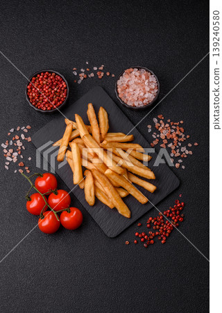 French fries, a salty, crispy, homemade snack with spices. French fries on a black background 139240580