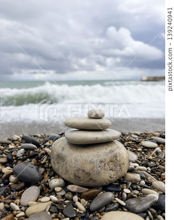 stones stacked in a pyramid on a pebble beach overlooking the raging sea stones stacked in a pyramid on a pebble beach overlooking the raging sea 139240941