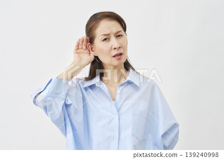 一位老婦人用手摀住耳朵，背景是白色。 139240998
