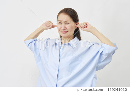 Elderly woman covering her ears on a white background Elderly woman covering her ears on a white background 139241010