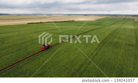 Work in progress. Aerial view of beet harvester on the green agricultural field 139241057