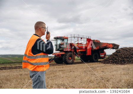 Conversation by walkie talkie. Farmer is working in the agricultural field. Against beet harvester 139241084
