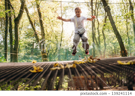Wellness conception. Little girl is playing on the children's amusement ropes course Wellness conception. Little girl is playing on the children's amusement ropes course 139241114