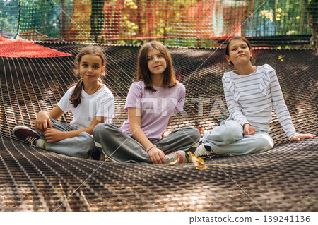 Looking forward, sitting, relaxed. Kids are playing on the children's amusement ropes course Looking forward, sitting, relaxed. Kids are playing on the children's amusement ropes course 139241136