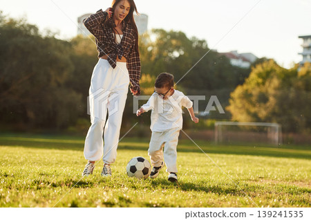 Weekend activities, playing soccer. Mother and son together in an open field during daytime Weekend activities, playing soccer. Mother and son together in an open field during daytime 139241535