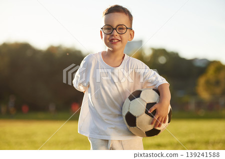 Game of soccer, with ball, competitive sport. Boy is having fun on the field under sunlight at daytime Game of soccer, with ball, competitive sport. Boy is having fun on the field under sunlight at daytime 139241588
