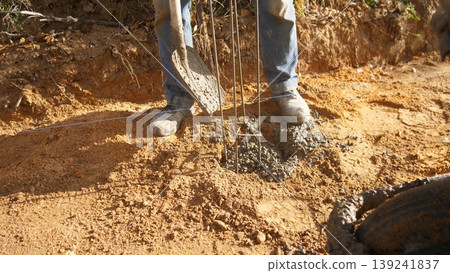 worker drills soil, person operating soil drill in sunlight, individual with tools boring into dry earth surface, worker carefully operating earth auger in soil with scattered gravel nearby worker drills soil, person operating soil drill in sunlight, individual with tools boring into dry earth surface, worker carefully operating earth auger in soil with scattered gravel nearby 139241837