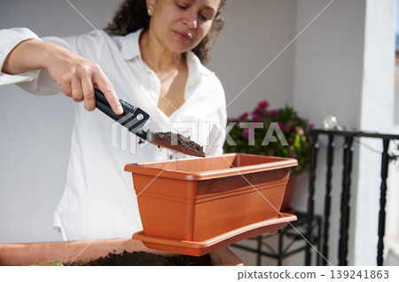 Woman Filling Planter With Soil On Balcony While Gardening With Trowel Woman Filling Planter With Soil On Balcony While Gardening With Trowel 139241863