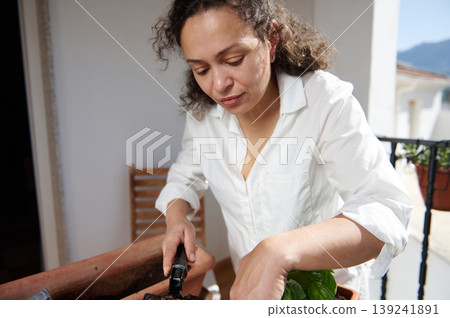 Woman Gardening On Balcony Planting Herbs With Trowel And Pot Woman Gardening On Balcony Planting Herbs With Trowel And Pot 139241891