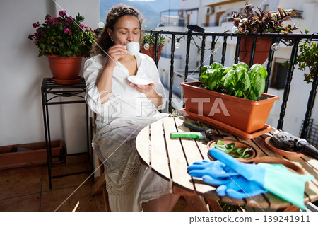 Woman Relaxing With Coffee on Balcony Among Potted Plants and Gardening Tools Woman Relaxing With Coffee on Balcony Among Potted Plants and Gardening Tools 139241911