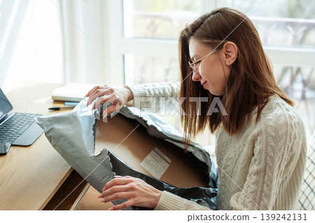 Woman unboxing package after online shopping at home 139242131