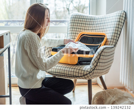 Woman packing clothes into suitcase for travel trip Woman packing clothes into suitcase for travel trip 139242132