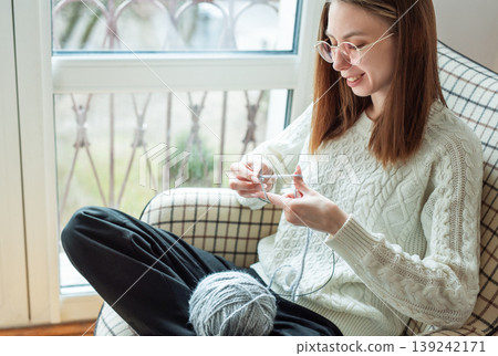 Woman knitting new sweater with gray yarn at home Woman knitting new sweater with gray yarn at home 139242171