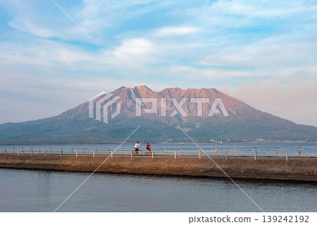 Evening scenery of Yojirogahama Long Waterway and Sakurajima (Kagoshima City - Parent and child on bicycles and calm water surface) Evening scenery of Yojirogahama Long Waterway and Sakurajima (Kagoshima City - Parent and child on bicycles and calm water surface) 139242192