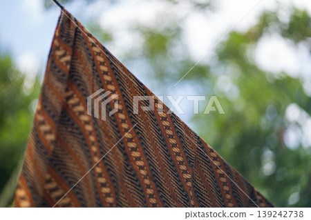 Traditional Patterned Fabric Hanging Outdoors with Blurred Green Nature Background Traditional Patterned Fabric Hanging Outdoors with Blurred Green Nature Background 139242738