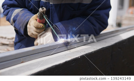 Closeup Welder Torch Cutting Steel Frame For House Construction, Protective Gloves Guide Arc As Bright Sparks Fly, Focused Hand Shaping Structural Beam In Workshop Environment. Closeup Welder Torch Cutting Steel Frame For House Construction, Protective Gloves Guide Arc As Bright Sparks Fly, Focused Hand Shaping Structural Beam In Workshop Environment. 139243149