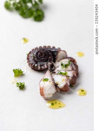 Boiled octopus sliced tentacles on plate top view. Olive oil and parsley dressing. Fresh seafood dish 139243404