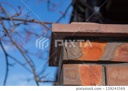Cracked orange brick pillar. Weathered masonry wall detail with structural damage. Damaged texture of building material and architectural decay. Abstract construction exterior element. Cracked orange brick pillar. Weathered masonry wall detail with structural damage. Damaged texture of building material and architectural decay. Abstract construction exterior element. 139243569