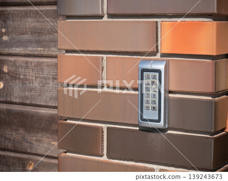 Electronic keypad mounted on brick wall. Security system for access control and home safety. Digital passcode device for gate door entry. Secure technology for property protection. Electronic keypad mounted on brick wall. Security system for access control and home safety. Digital passcode device for gate door entry. Secure technology for property protection. 139243673
