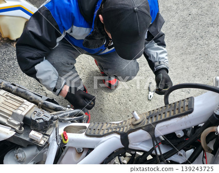 Mechanic repairing motorcycle engine. Man fixing bike frame with tool. Workshop maintenance of vehicle. Technical service, engineering and hobby concept. Troubleshooting and transport repair. Mechanic repairing motorcycle engine. Man fixing bike frame with tool. Workshop maintenance of vehicle. Technical service, engineering and hobby concept. Troubleshooting and transport repair. 139243725