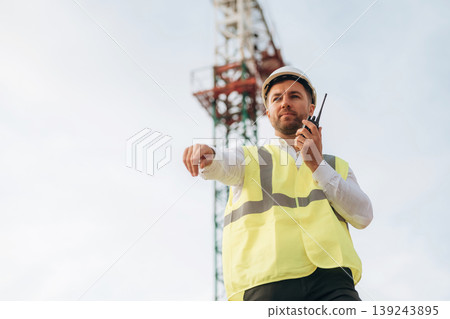 Construction site worker is against building crane and sky background 139243895
