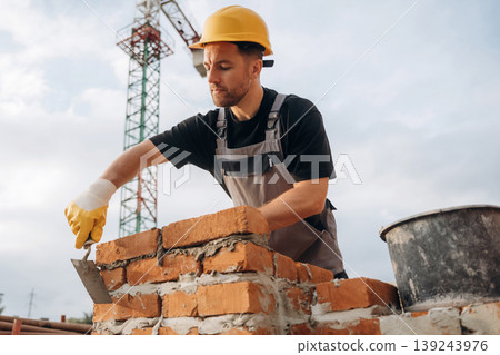 Bunch of bricks, busy. A builder is working at the construction site at daytime Bunch of bricks, busy. A builder is working at the construction site at daytime 139243976