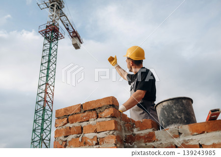 Cloudy sky behind. A builder is working at the construction site at daytime 139243985