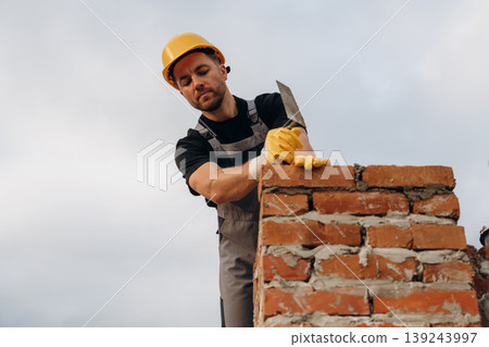 In yellow colored protective helmet. A builder is working at the construction site at daytime 139243997
