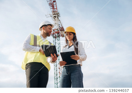 Man and woman, construction site workers are against crane, communication Man and woman, construction site workers are against crane, communication 139244037