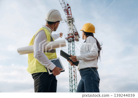 Man and woman, construction site workers are against crane, communication Man and woman, construction site workers are against crane, communication 139244039