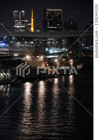 A night view of Tokyo Bay, including a moored Japan Coast Guard patrol boat and the Tokyo Tower, overlooking the waterfront sub-city center. 139244189