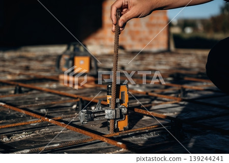 On metal rods. Close up view of man's hand that is using leveling tool on the floor, construction site On metal rods. Close up view of man's hand that is using leveling tool on the floor, construction site 139244241