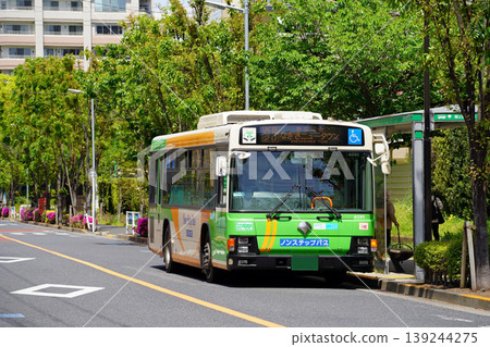 A Toei bus (wide) parked at a bus stop surrounded by greenery. A Toei bus (wide) parked at a bus stop surrounded by greenery. 139244275