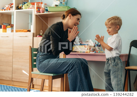 Woman is sitting and checking the boy. Preschool child with teacher during developmental activities in a playroom 139244282