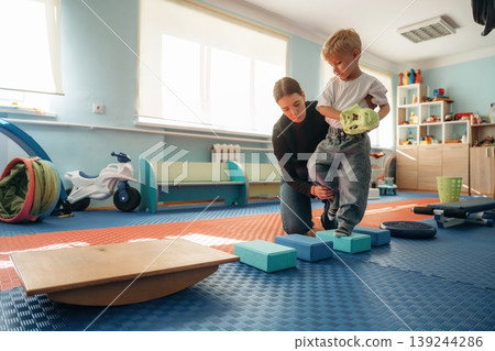 Balancing, walking. Preschool child with teacher during developmental activities in a playroom Balancing, walking. Preschool child with teacher during developmental activities in a playroom 139244286