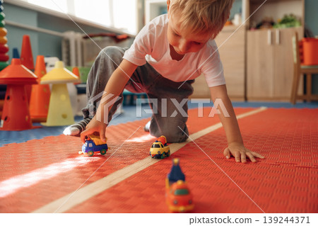 Playing with toy cars. Cute preschool child, boy, during developmental activities in a playroom Playing with toy cars. Cute preschool child, boy, during developmental activities in a playroom 139244371