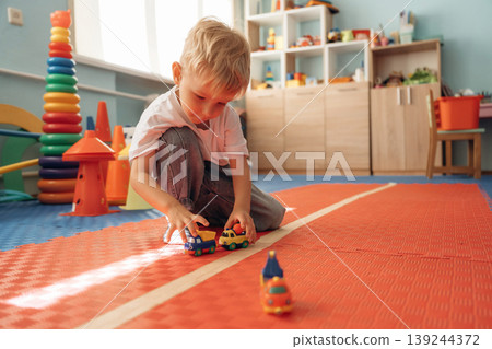 Playing with toy cars. Cute preschool child, boy, during developmental activities in a playroom 139244372