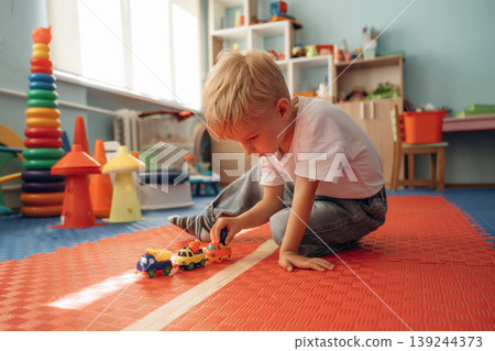 Playing with toy cars. Cute preschool child, boy, during developmental activities in a playroom Playing with toy cars. Cute preschool child, boy, during developmental activities in a playroom 139244373