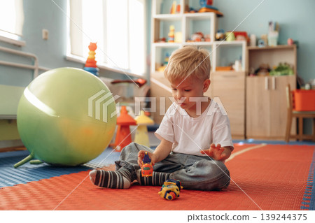 Playing with toy cars. Cute preschool child, boy, during developmental activities in a playroom Playing with toy cars. Cute preschool child, boy, during developmental activities in a playroom 139244375